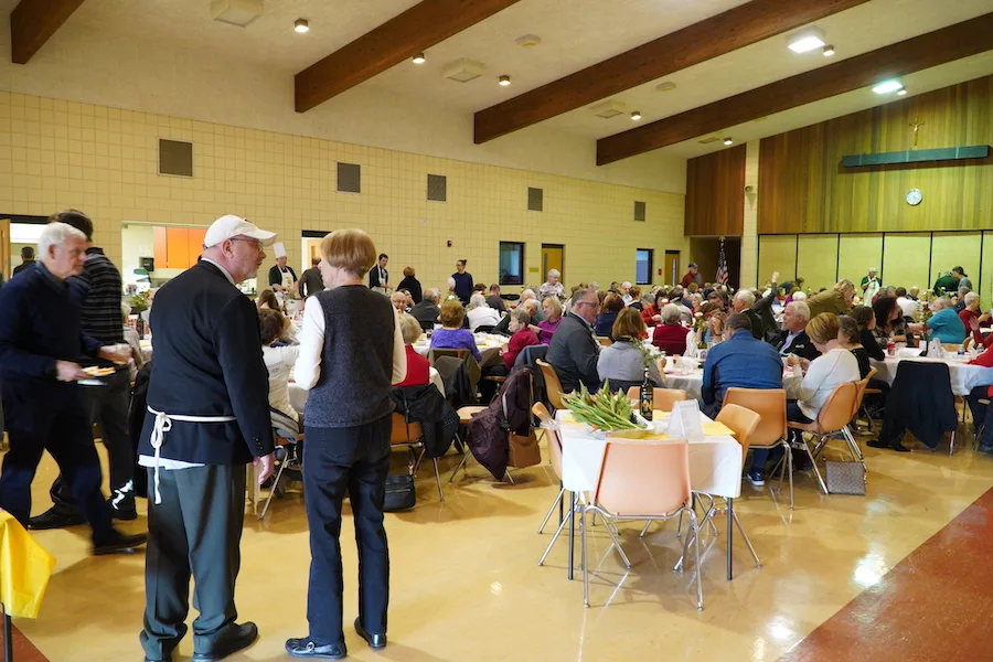Parishioners seated at round tables filling the parish hall during a council dinner