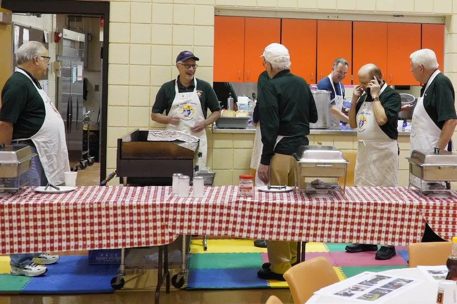Council members in green shirts and aprons setting up the serving tables before a parish dinner