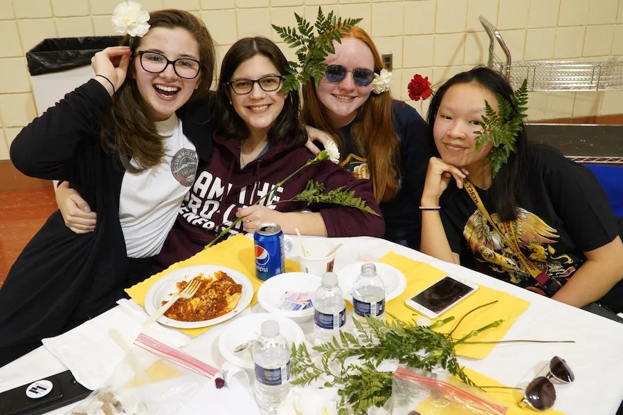 Four young parishioners smiling together at a table during a parish dinner